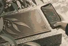 Phone testing a discreet QR detail on a bronze plaque